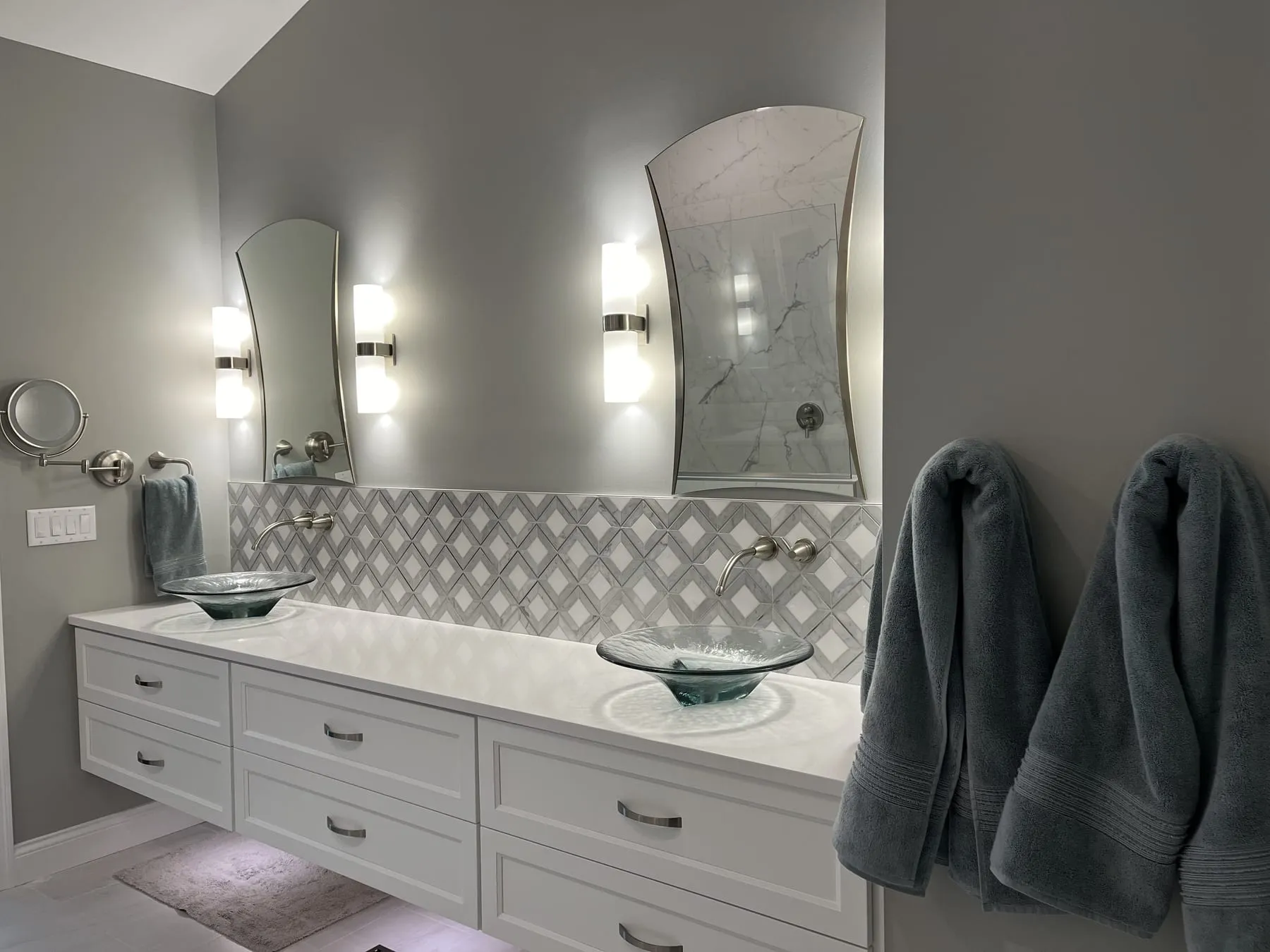 Double-vanity bathroom with soft gray walls and a tiled backsplash