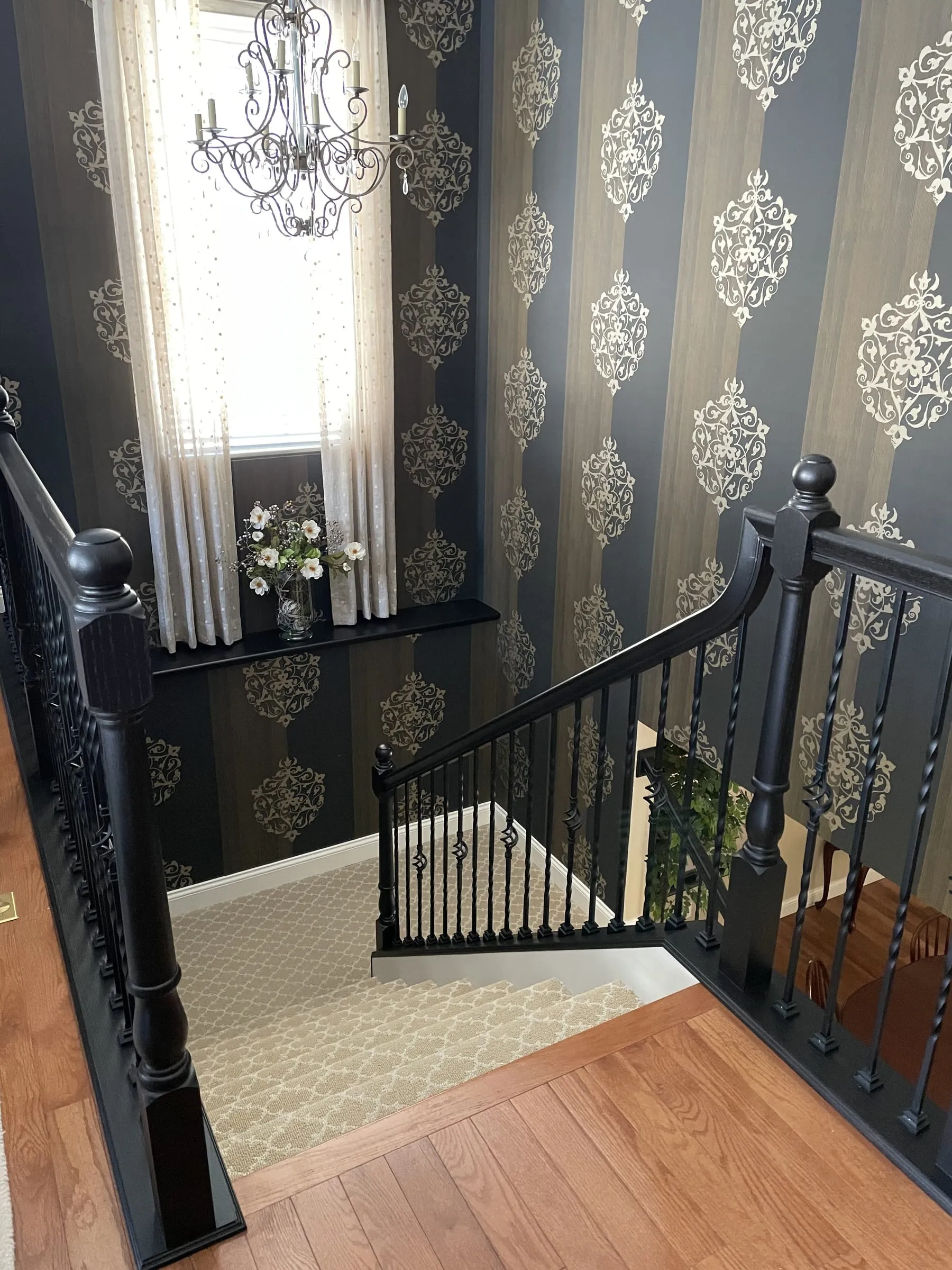 Bold black staircase and railing against patterned wallpaper